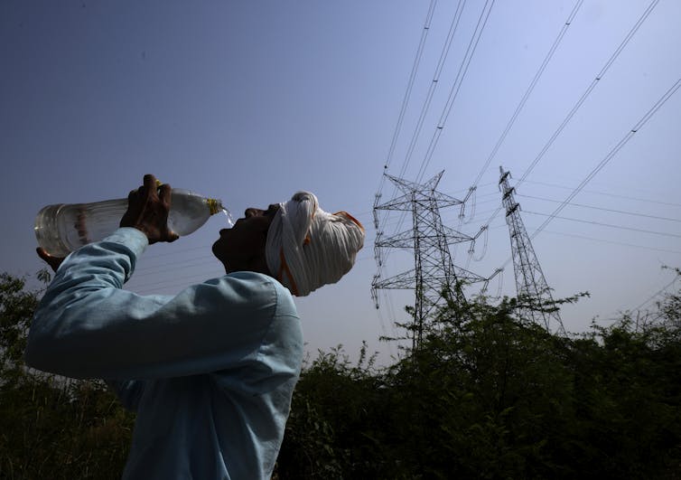 A man drinks water near powerlines