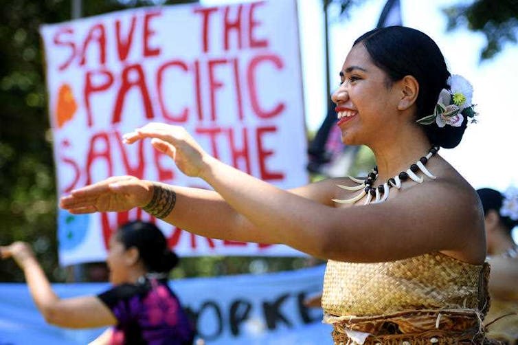 woman dances in front of climate action sign