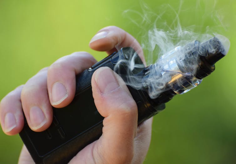 hand with e-cigarette and vapour