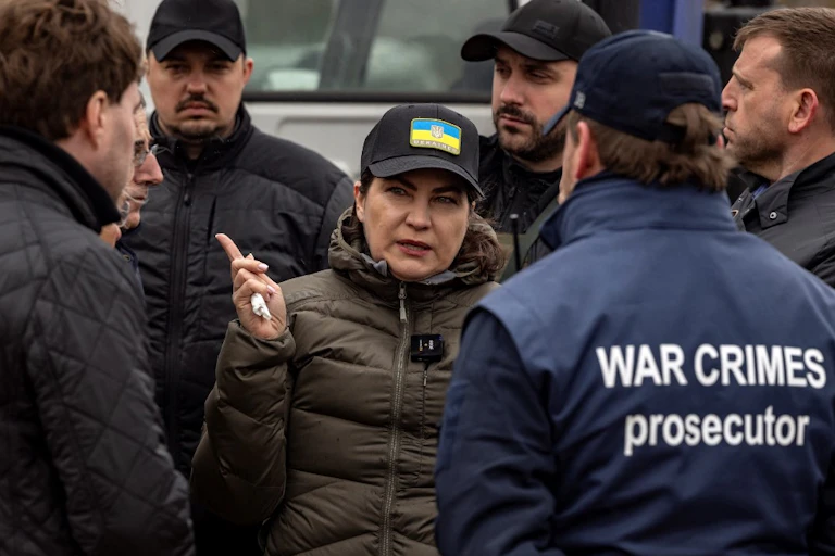 La procureure d'Ukraine sur le terrain, devant un homme avec une veste portant ll'inscritpion War Crimes prosecutor