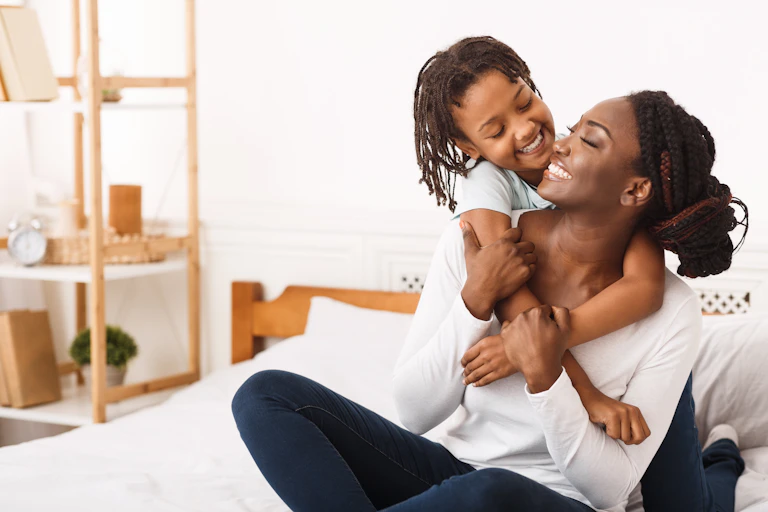 a woman and child hugging on a bed