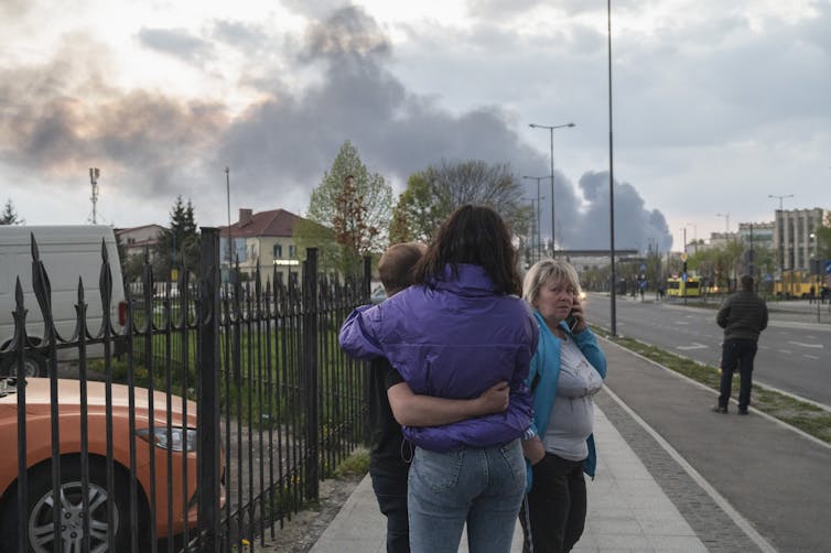 people look at clouds of smoke with arms around each other