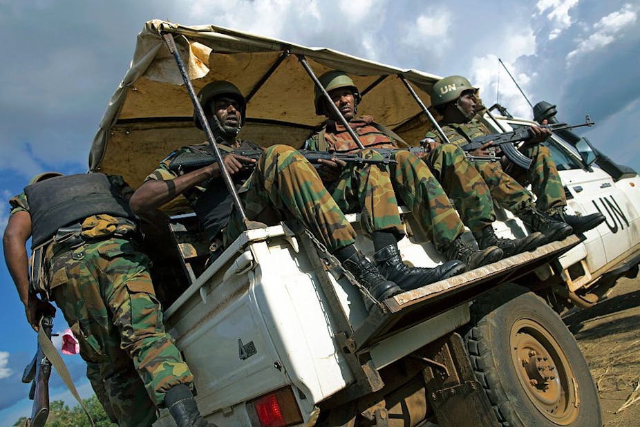 Soldiers in UN vehicle carrying guns.