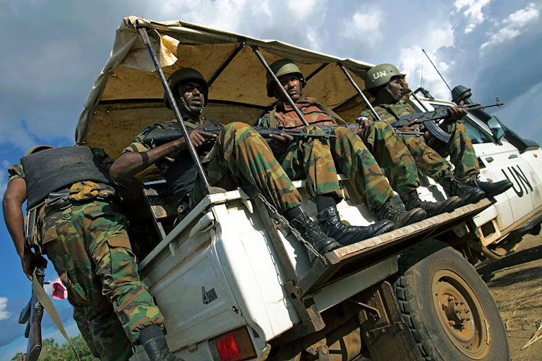 Soldiers in UN vehicle carrying guns.