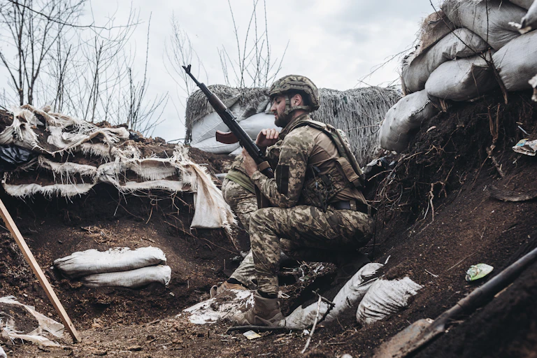 A Ukrainian soldier checks his rifle while on guard in a trench.