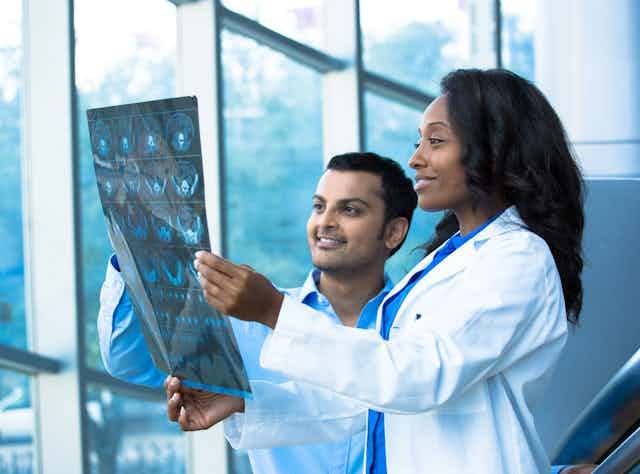 A woman and a man in white coats looking at medical images