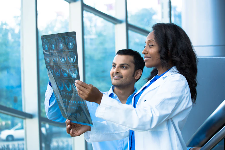 A woman and a man in white coats looking at medical images