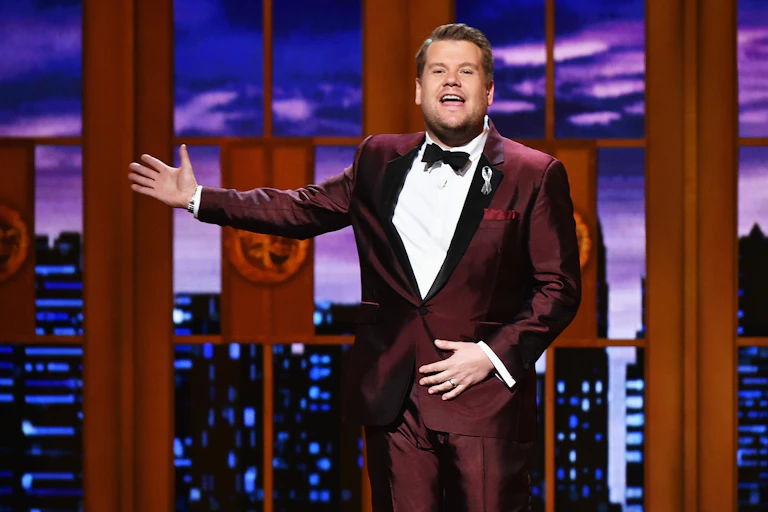 Men in red tuxedo gestures on stage.