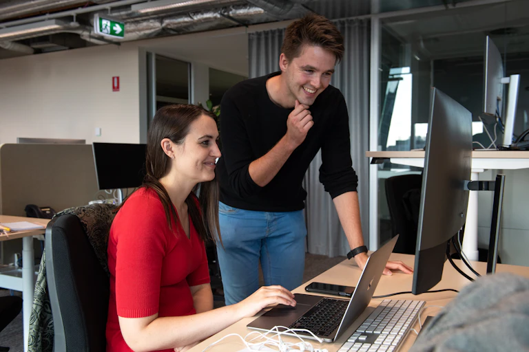 Two editors from The Conversation standing in front of a computer.