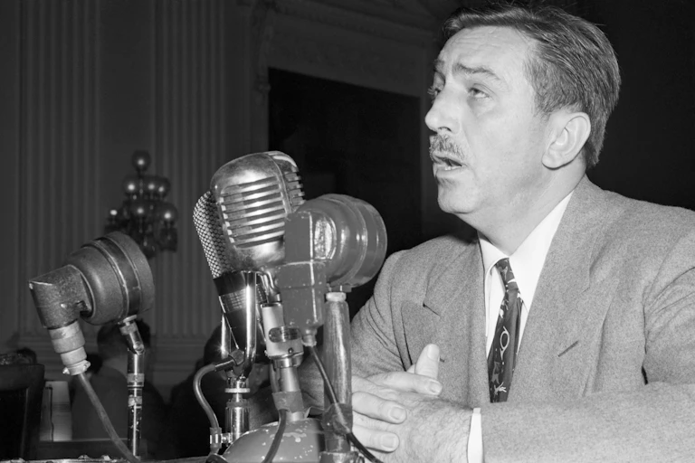 Man speaks before mutliple microphones during a hearing.