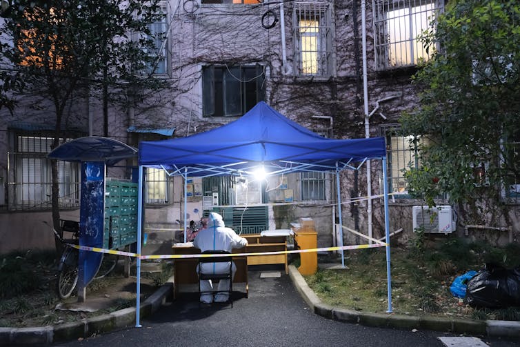 Medical worker sits outside residential building in Shanghai
