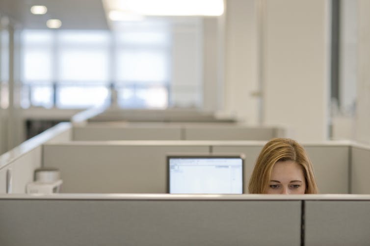 Woman sitting in a cubicle.