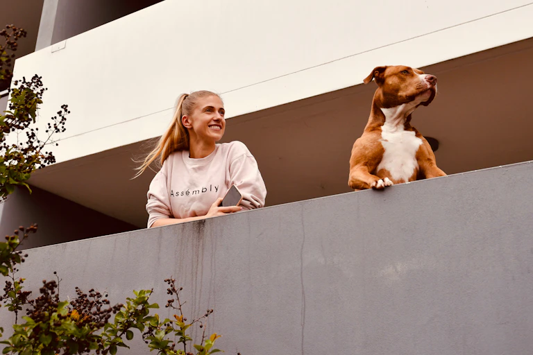 woman and dog look from apartment balcony