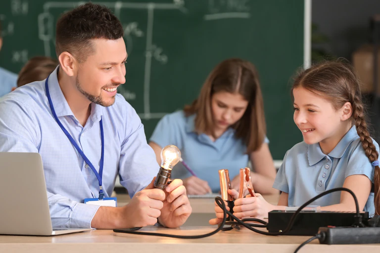 Girls and teacher in physics class with lightbulb