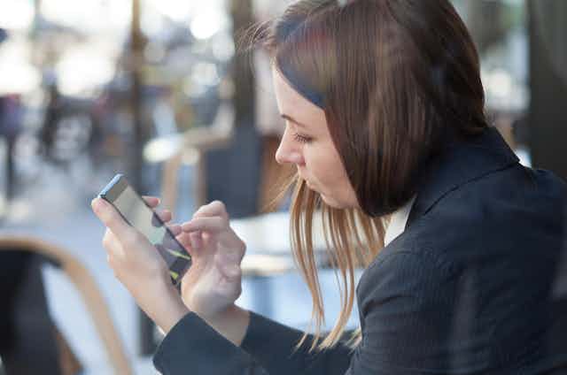 Women using a smartphone outside a restaurant
