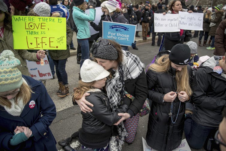 Anti-abortion protestors carrying banners expressing love for life.