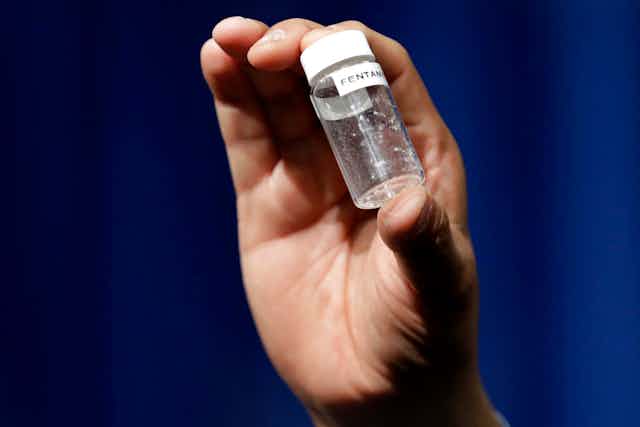Hand holding a vial containing a lethal dose of fentanyl.