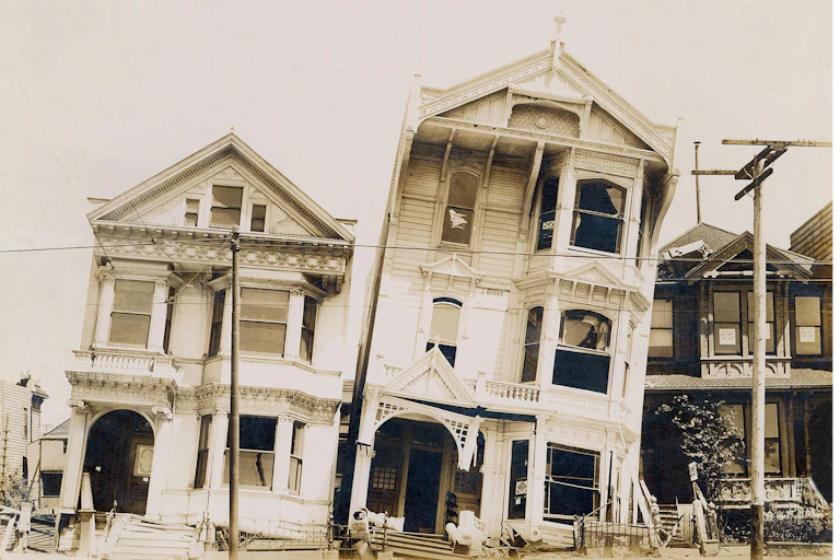 A black and white photo of tilting wooden houses.