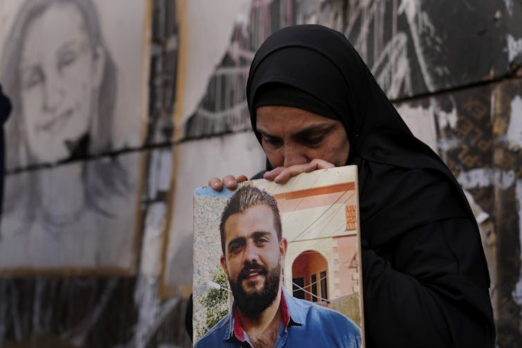 Une femme en pleurs tient une photo d’un jeune homme