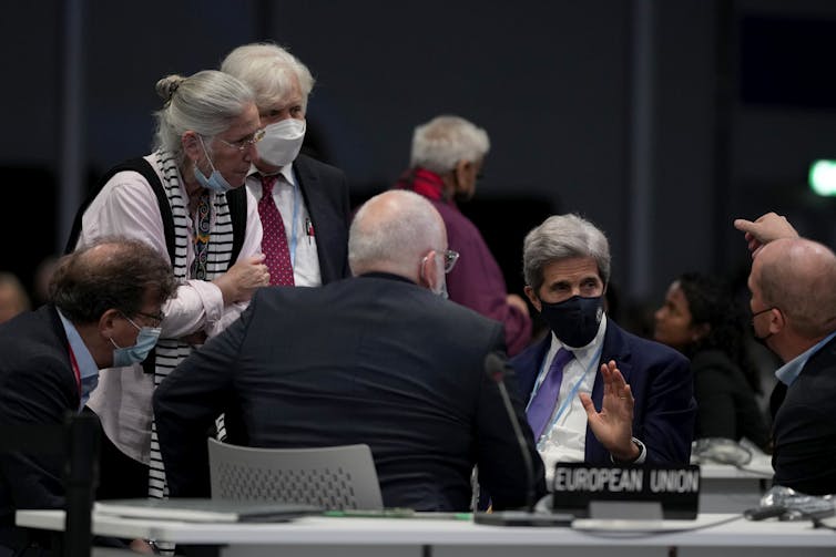 Men and women talking in a conference room with table placemarker reading