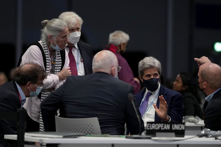 Men and women talking in a conference room with table placemarker reading 