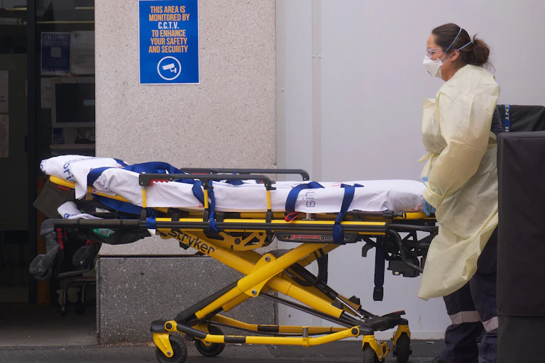 Woman in PPR wheeling hospital gurney