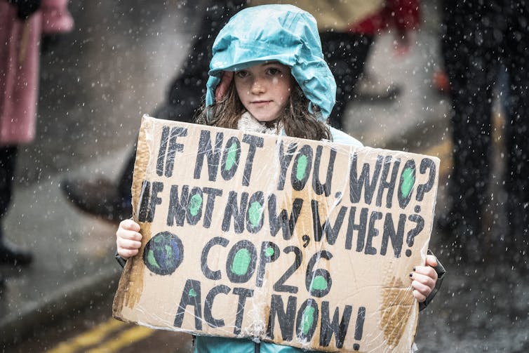 Girl in raincoat holds sign