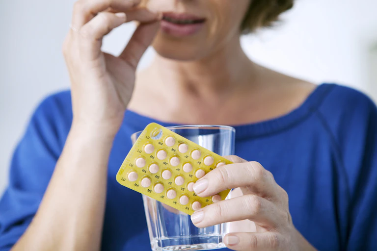 A woman takes a tablet.
