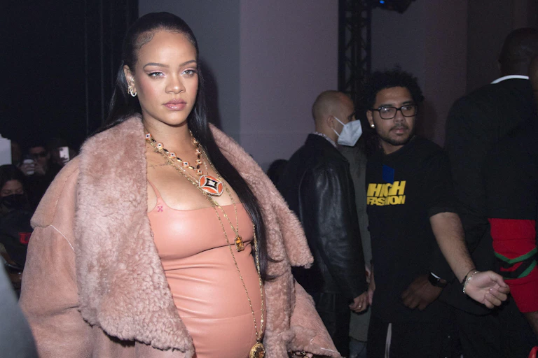 Pregnant woman in pink dress and pink suede coat.