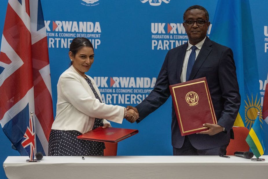 British Home Secretary Priti Patel (L), and Rwandan Minister of Foreign Affairs and International Cooperation Vincent Biruta, shake hands after signing an agreement at Kigali 