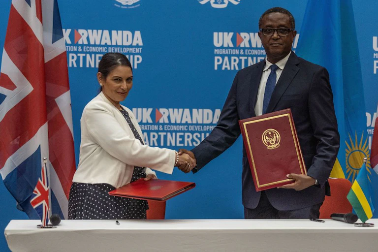 British Home Secretary Priti Patel (L), and Rwandan Minister of Foreign Affairs and International Cooperation Vincent Biruta, shake hands after signing an agreement at Kigali