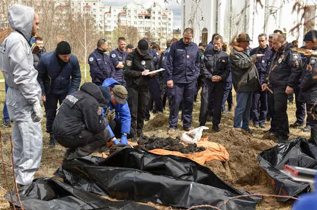 Forensic investigators examine bodies taken from a mass grave in Bucha, April 2022.