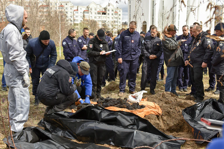 Forensic investigators examine bodies taken from a mass grave in Bucha, April 2022.