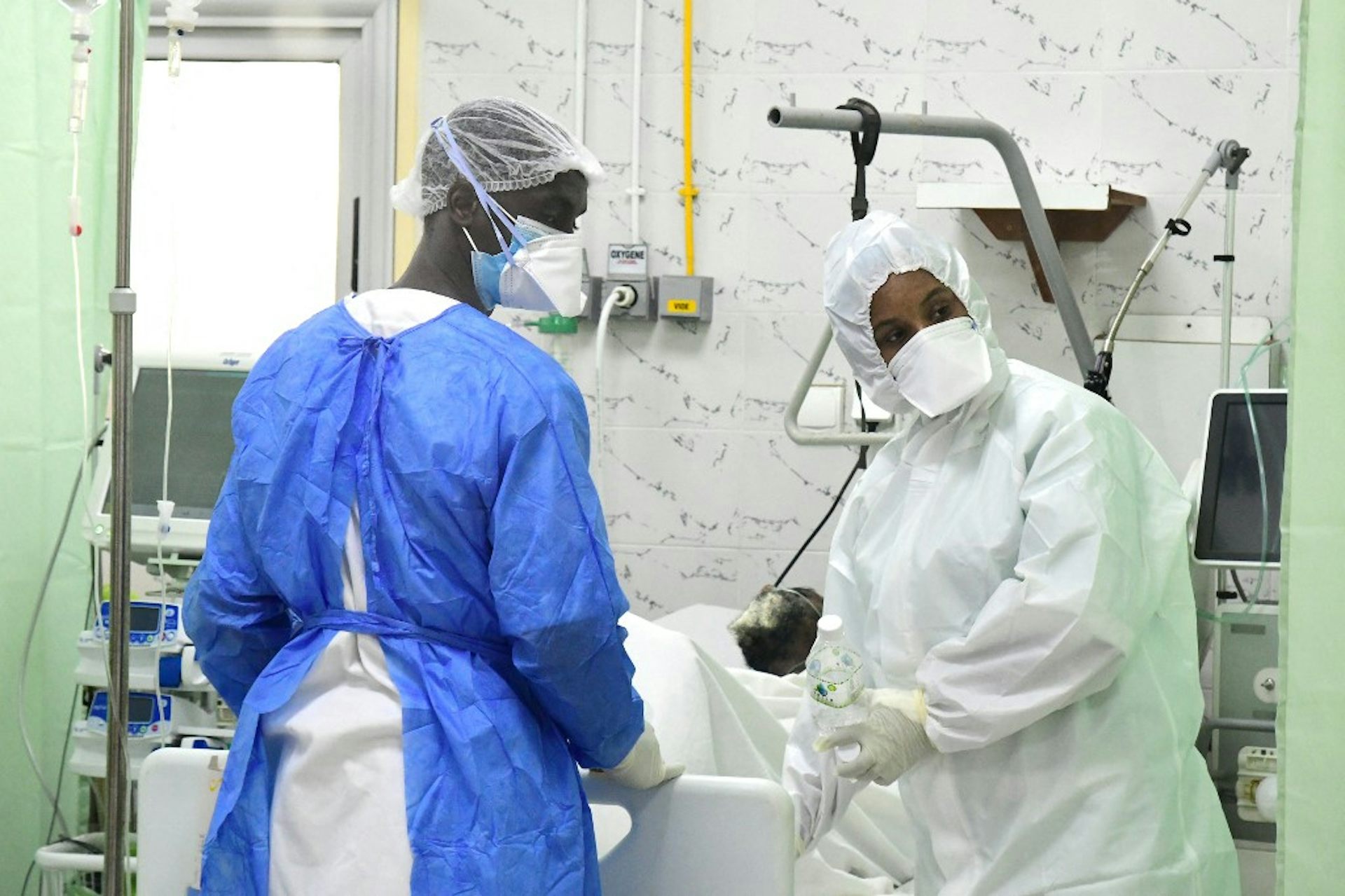 Deux soignants noirs en tenues stérilisées sont dans une zone de soins intensifs