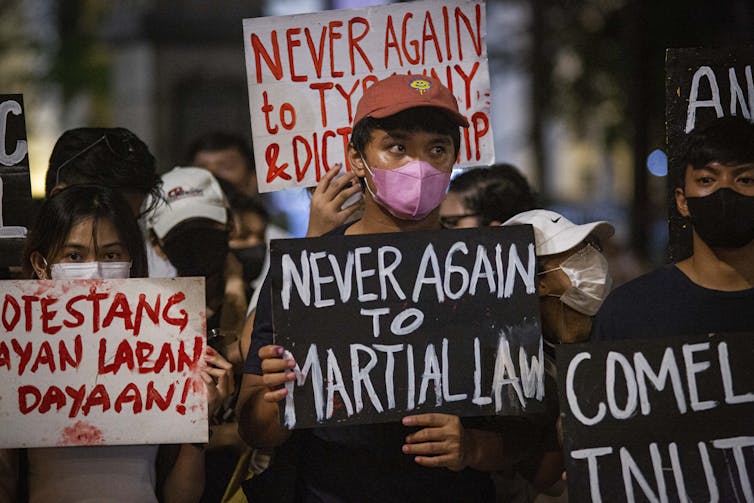 Protesters gather holding signs saying 'Never Again to Martial Law.'