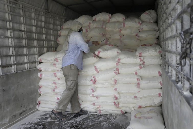 Un homme de dos charge des sacs de farine dans un camion