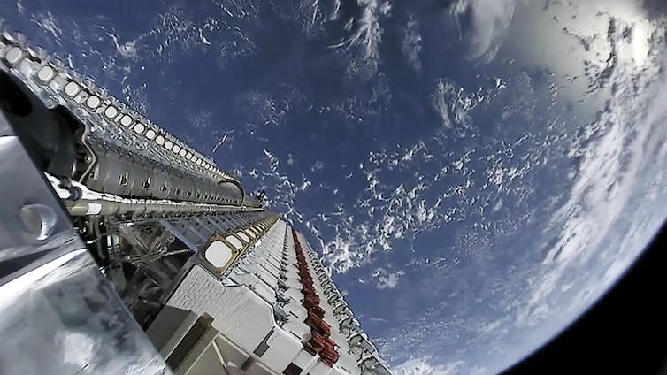 A row of small satellites attached to a rocket with Earth in the background.