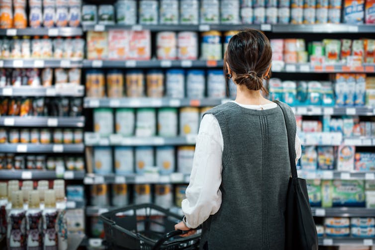 Woman standing in front of supermarket shelves.