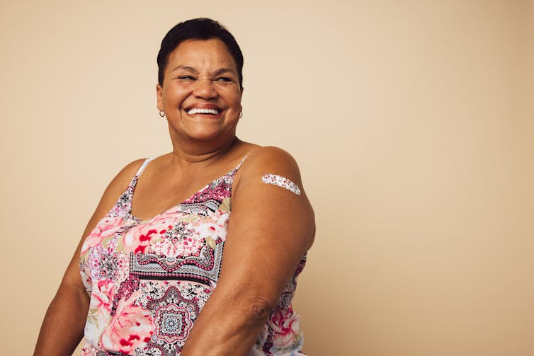 Middle-aged lady smiling with bandaid on upper arm