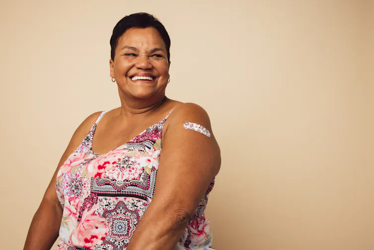 Middle-aged lady smiling with bandaid on upper arm