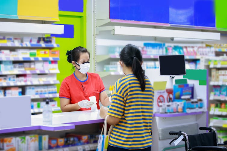 Patient talks to a pharmacist at the counter.