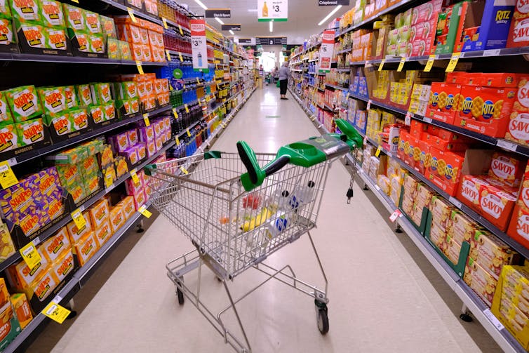 supermarket aisle with trolley and junk food shown