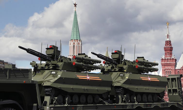 Robotic tanks carried on the back of a lorry through a city.