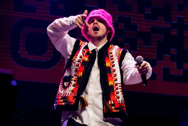 A man singing wearing a pink hat.