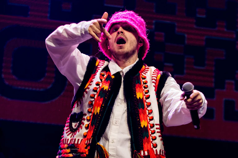 A man singing wearing a pink hat.