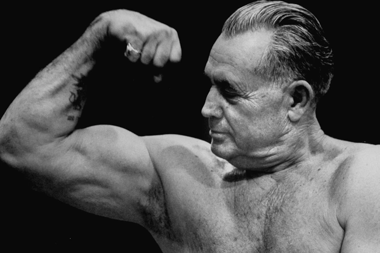 Older man flexes bicep.
