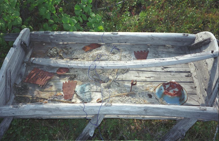 A number of small objects are scattered around the top of a sleigh sitting in a field.