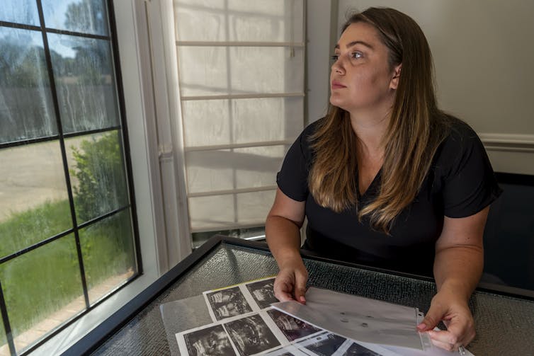 A woman sits with images of ultrasounds