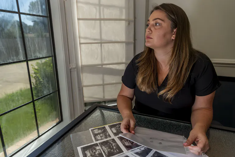 A woman sits with images of ultrasounds