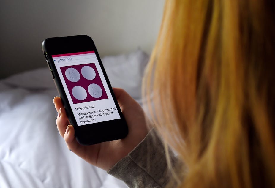 A woman looks at Mifepristone, an abortion pill for unintended pregnancy, on her phone screen.